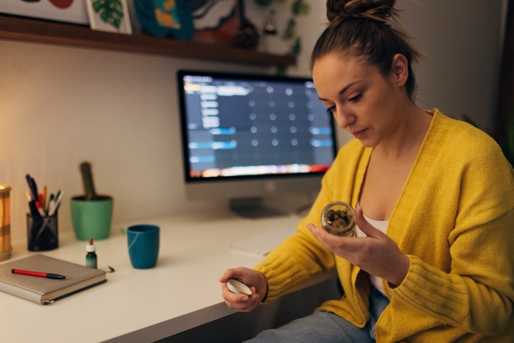 woman holding cannabis in front of computer remote cannabis jobs