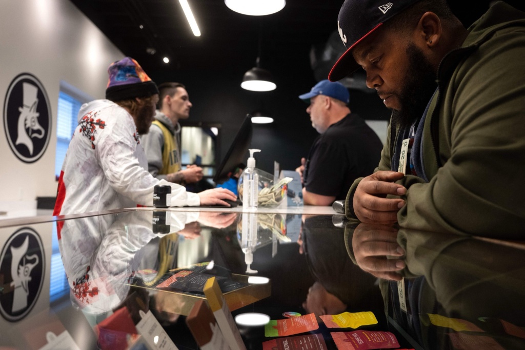 man looks at different cannabis branding in dispensary