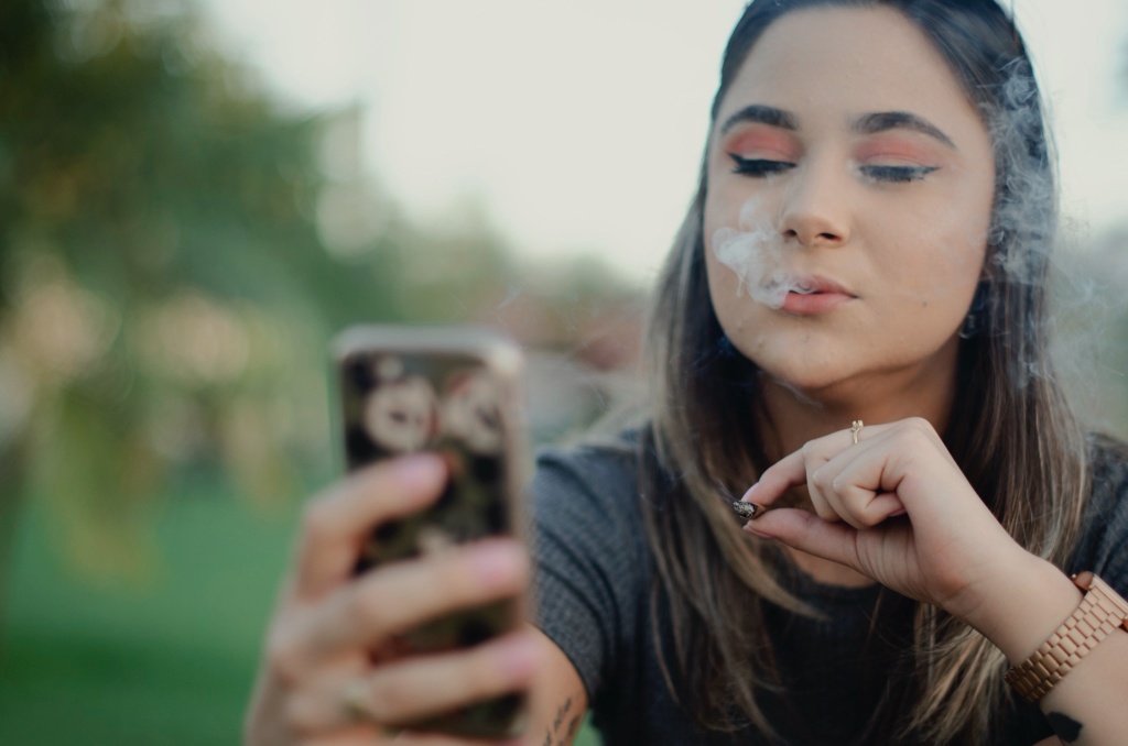 woman smoking while on phone cannabis social media