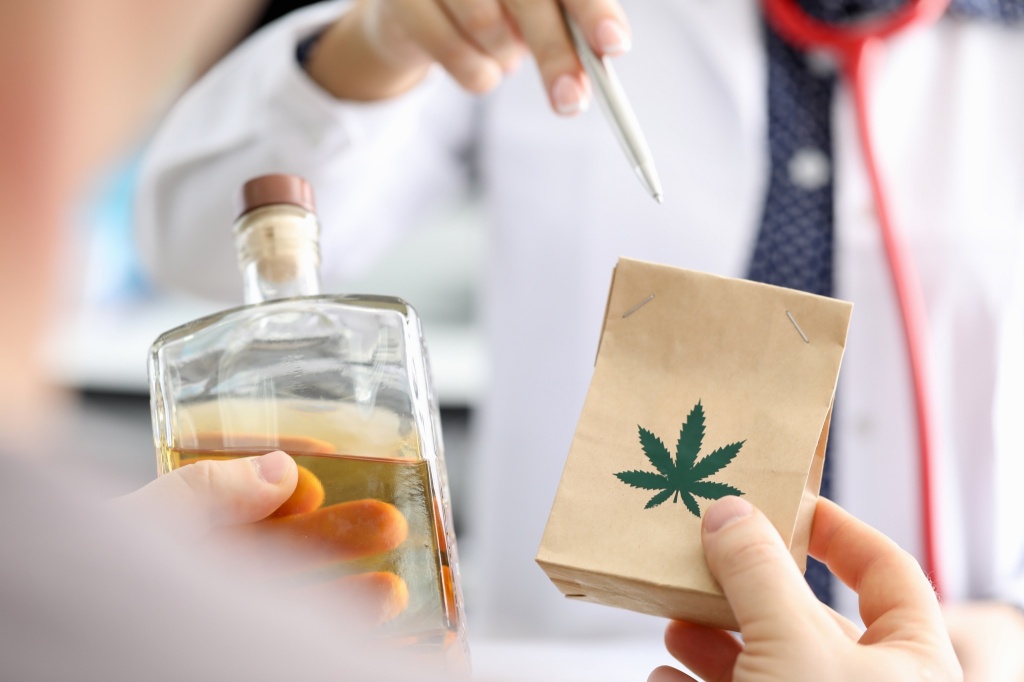 hand holding alcohol and bag of cannabis study shows alcohol may curb desire to drink