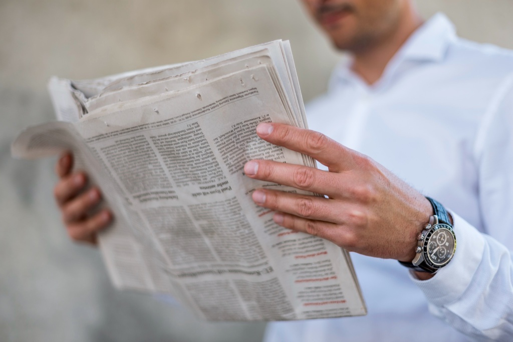 person reading earned media in newspaper