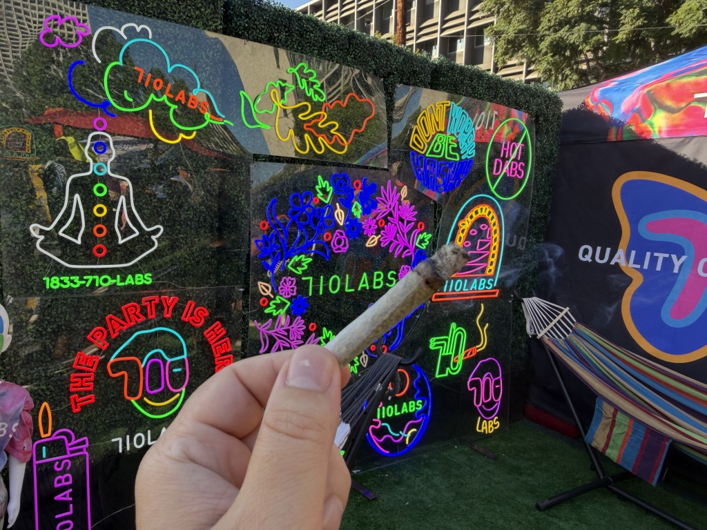 holding joint in front of 710 labs signs at Puffcon 2026